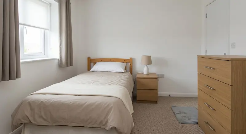 Generic, anonymous UK holiday let bedroom — clean but characterless, unable to justify a premium nightly rate after FHL tax changes